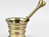 un mortier et un pilon anciens en laiton sur fond blanc