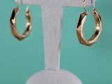 un gros plan sur une paire de boucles d'oreilles créoles en or posées sur un présentoir