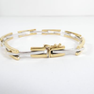 a close up of a gold and silver bracelet on a white surface
