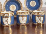 six blue and white cups with gold trims and a monogram on them