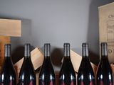 six bottles of red wine are lined up on a table
