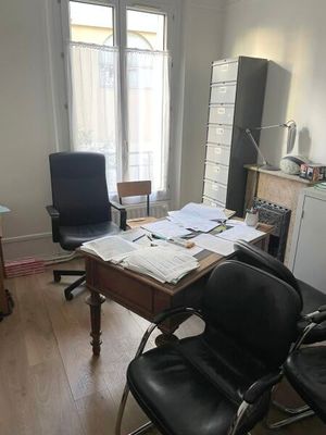 a desk with two chairs and a desk top with papers on it