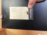 a person pointing at a piece of paper on a piece of wood