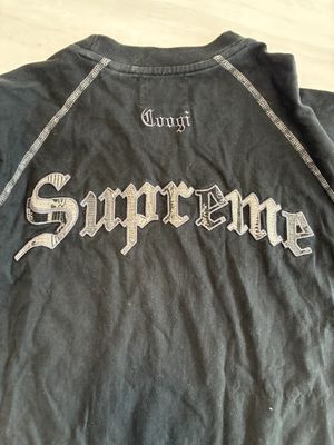 le dos d'un t-shirt noir sur lequel est inscrit le mot « Supreme »
