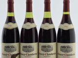quatre bouteilles de vin rouge sont alignées sur une table