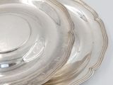 three silver plates with a silver rim on a white surface