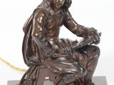 une image représentant une statue en bronze d'un homme assis sur un rocher