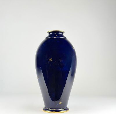 a blue vase with a gold rim sitting on a white surface