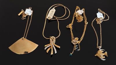 plusieurs colliers et pendentifs en or posés sur un fond noir