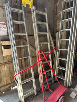 many ladders and a dolly in a garage