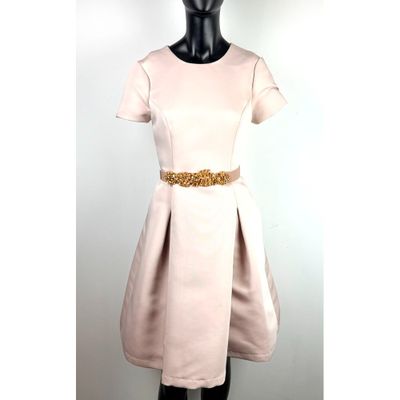 Le mannequin porte une robe avec une ceinture dorée.