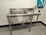 a stainless steel sink in the corner of a room