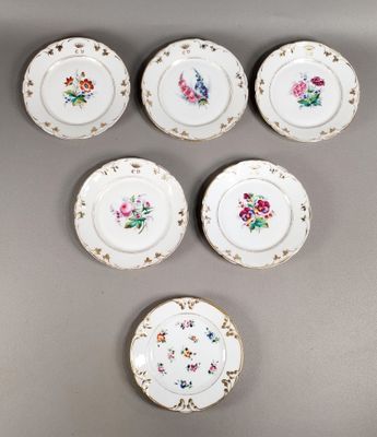 six petites assiettes ornées de motifs floraux sont disposées sur un fond gris