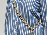 a picture of a woman wearing a blue and white striped shirt and a gold chain necklace