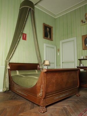 un lit surmonté d'un baldaquin, dans une chambre