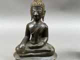 two statues of buddhas sitting on top of a wooden base