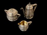 three silver teapots and a sugar bowl on a black background
