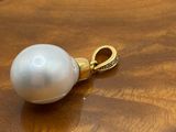 pearl pendant on a wooden table with a gold chain
