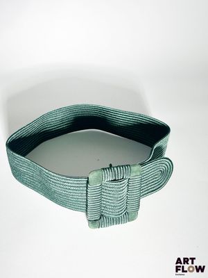 une ceinture verte ornée d'un nœud, posée sur un fond blanc