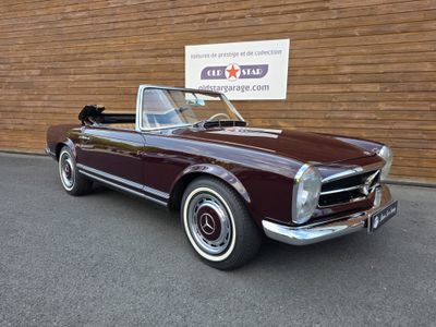 an image of a maroon convertible car parked in front of a building