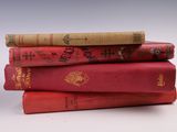 trois livres rouges empilés les uns sur les autres sur une surface blanche