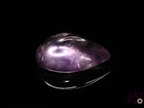 un gros plan d'un quartz violet posé sur une surface noire
