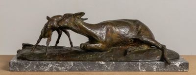 a bronze statue of a goat laying on a rock