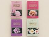 three books on a white surface with pink and purple flowers on them