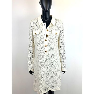 une photo d'un mannequin portant une robe blanche à boutons dorés