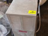 un petit climatiseur posé par terre à côté d'un ventilateur