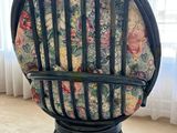 a black chair with a floral cushion on it in front of a window