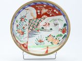 a plate with a bird and flowers on it on a stand