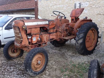 un vieux tracteur rouillé garé devant un bâtiment