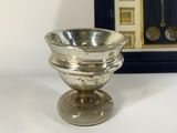 a small silver bowl sitting next to a framed picture