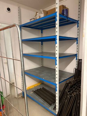 une étagère métallique placée dans un coin de la pièce, comportant plusieurs tablettes