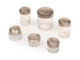 six glass jars with silver lids and lids on a white surface