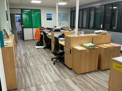 many desks and chairs in this office with a lot of clutter