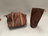 two brown bags and a pair of brown boots sitting on a table