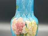 a blue vase with yellow and pink flowers painted on it