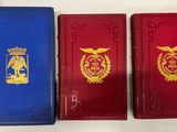 trois livres rouges et bleus posés sur une table blanche
