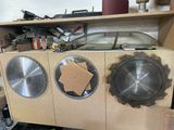 trois lames de scie circulaire posées sur un établi