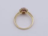 a yellow gold ring with a ruby and diamond center