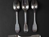 three silver spoons and a fork on a black surface