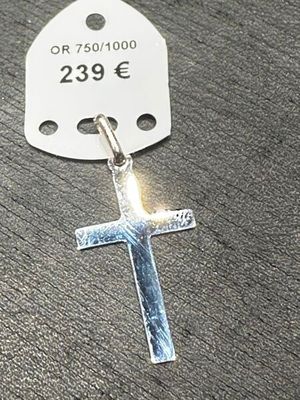 une croix en argent à laquelle est attachée une étiquette