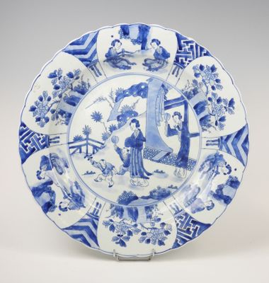 assiette bleue et blanche représentant une femme et un homme dans un jardin