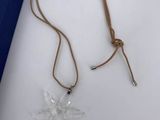 the necklace is made of glass and has a brown cord around it