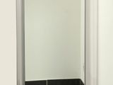 un miroir dans un coin de la salle de bains, dont le sol est carrelé de noir