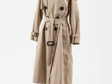 un trench-coat beige posé sur un mannequin, devant un fond blanc