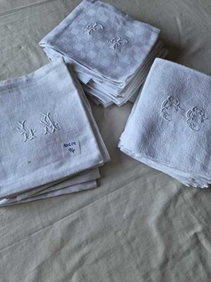 quatre serviettes blanches ornées de monogrammes brodés, posées sur un lit