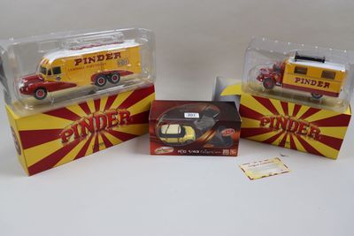 trois camions de pompiers miniatures dans leurs boîtes, posés sur une surface blanche